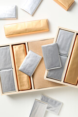 Chocolate candies in foil and in boxes on white background, top view