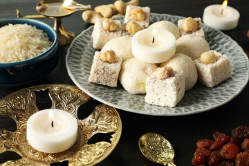 Sweets, rice, candles and copper utensils on dark wooden background, close up