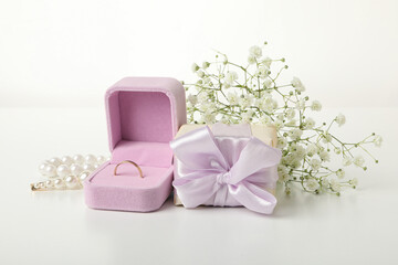 Obraz na płótnie Canvas Wedding ring in case, flowers and gift box on white background