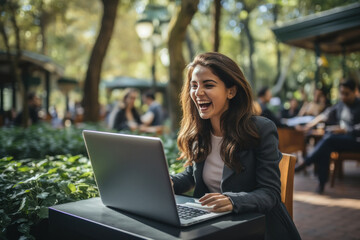 Indian young woman laughing while using laptop.