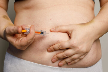 Woman holding syringe making self injection in belly. Health care, medicine treatment, hormonal therapy, in vitro fertilization