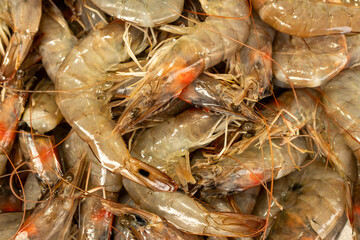 Unpeeled king prawns, popular seafood, on display at a market stall.