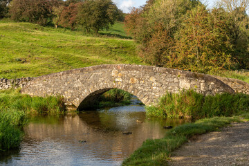 A peaceful and serene landscape in the evening sun of  a stone bridge over the river Bradford in Derbyshire