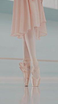 Close-up of ballerina's legs in pointe shoes. Ballerina is standing on tiptoe. Vertical video format for the phone.
