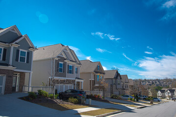 Quiet residential street leading down a steep hill with row of two-story houses, new development...