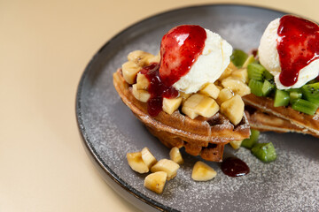 waffles with fruits and ice cream close up on a pale orange background