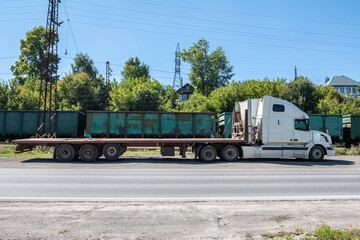 White long distance bonnet truck with a semitrailer at a freight railway station in the countryside