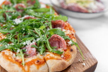 fine restaurant pizza on wooden board with salad, meat and mozzarella 