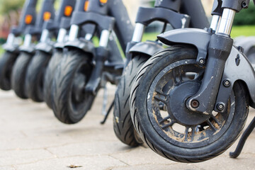 Wheels of many scooters stand on sidewalk © Vera Aksionava