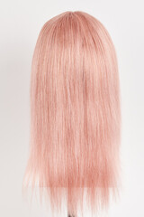 Natural looking pink blonde wig on white mannequin head. Long hair cut on the plastic wig holder isolated on white background
