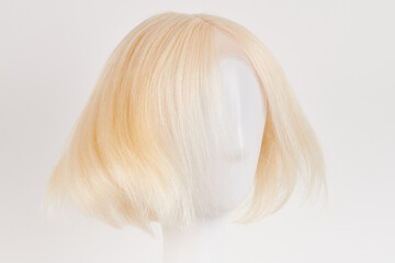 Natural looking blonde fair wig on white mannequin head. Short hair cut on the plastic wig holder...