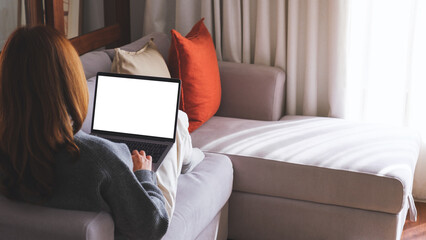 Mockup image of a woman working and typing on laptop computer with blank screen while sitting on...