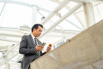 Asian businessman office worker in suit using mobile phone during walking city street at office district. Professional male executive using smartphone working corporate business communication.