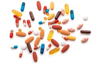 An isolated photo of a number of pain reliever and vitamin pills in different colors such as blue, yellow, red, etc.