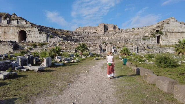 Young woman walk in ancient greek city on the western coast of Anatolia, look on antique amphitheater. Ancient theatre of Miletus, Didim, Aydın, T&uuml;rkiye
