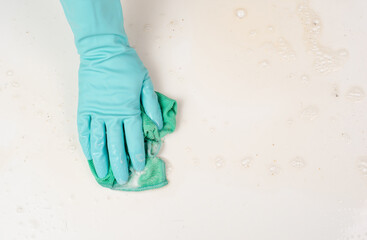 Employee with blue rubber protective glove whiping table with water and soap, cleaning dusty and...