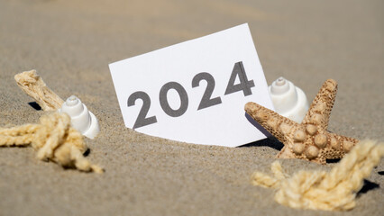 2024 text start new year symbol on paper greeting card on background of starfish summer vacation decor. Sandy beach sun coast. Holiday concept postcard. Getting away Travel Business concept
