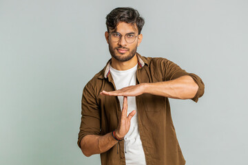 Tired serious upset Indian young man showing time out gesture, limit or stop sign, no pressure, I need more time, take a break, relax, rest, help. Arabian guy isolated on gray studio background - obrazy, fototapety, plakaty