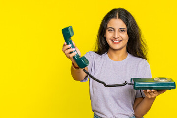 Hey you, call me back. Indian woman talking on wired landline vintage telephone of 80s, advertising proposition of conversation, online shopping, hotline. Arabian girl isolated on yellow background