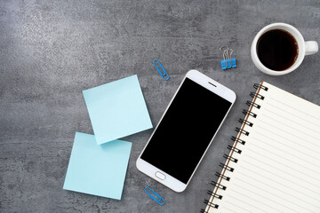 Mobile phone with blank mockup screen and book on stone texture background.Work desk. Top view. Flat lay.