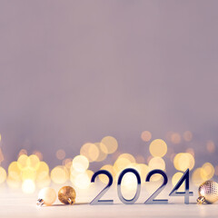 Metal numbers 2024 on a white table with Christmas decorations and bokeh lights. Happy New Year 2024 is coming concept.