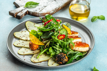 appetizer pear salad, greens and cheese on a light background top view. place for text