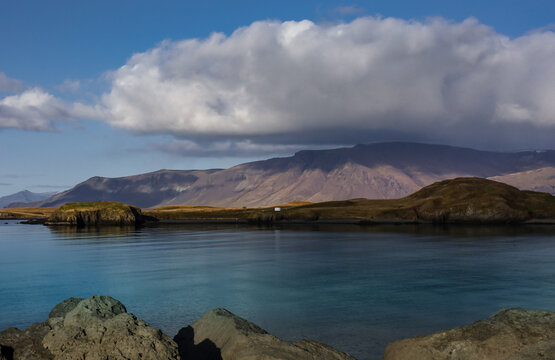 Landscape with Mount Esja and Atlantic ocean in Reykjavik, Iceland. Shining water, cloudy sky. 