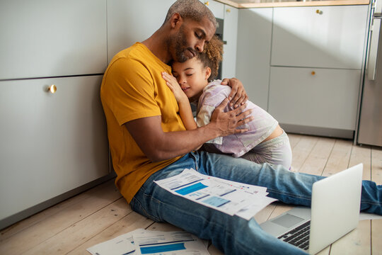 Young father embracing his daughter during a financial crisis on the floor at home