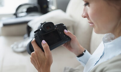Woman holds black professional camera in her hands. How to become professional photographer yourself from scratch concept - obrazy, fototapety, plakaty