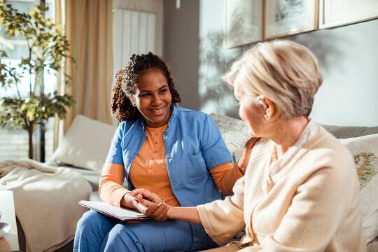 Senior woman consulting her caregiver on the couch at home