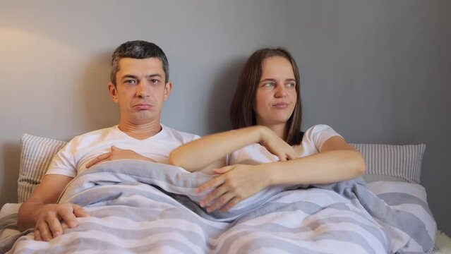 Dissatisfied female raising blanket looking at her husband erection sees problems erectile dysfunction or being disappointed of boyfriend genitals size.