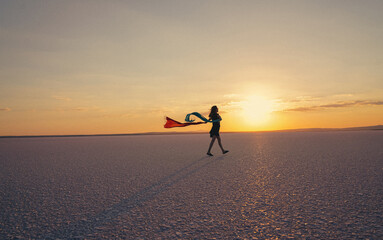 Young ballerina walking on the lake at sunset