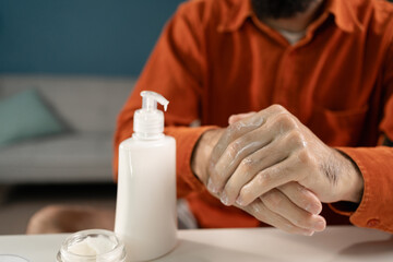 Close-up of a man applying moisturizer to his hands. Taking care of a man's body