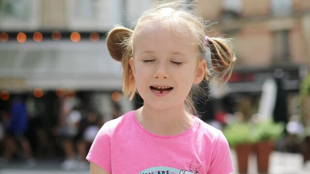 preschooler girl outdoors showing her missing front tooth