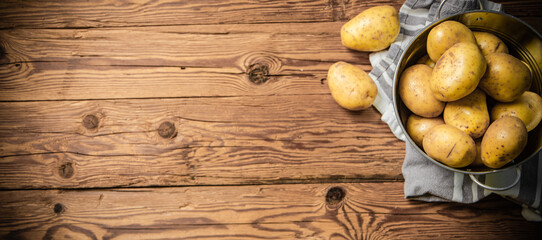 Fototapeta na wymiar Fresh potatoes. On wooden table.