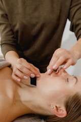 buccal facial massage, close-up, cosmetologist makes woman a procedure on a massage table in a spa salon
