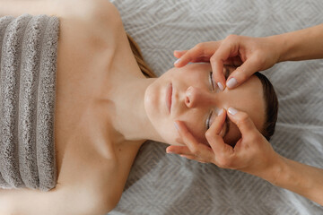 buccal facial massage, close-up, cosmetologist makes woman a procedure on a massage table in a spa salon