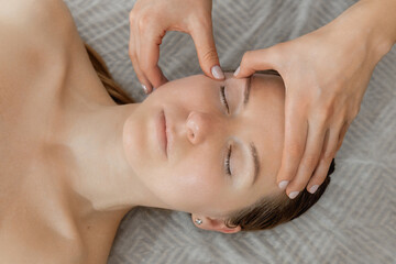 buccal facial massage, close-up, cosmetologist makes woman a procedure on a massage table in a spa salon