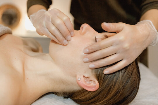 buccal facial massage, close-up, cosmetologist makes woman a procedure on a massage table in a spa salon