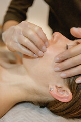 Fototapeta na wymiar buccal facial massage, close-up, cosmetologist makes woman a procedure on a massage table in a spa salon