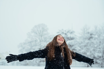 Fototapeta na wymiar cute girl having a fun with a snow in winter cold weather. Winter season joying.