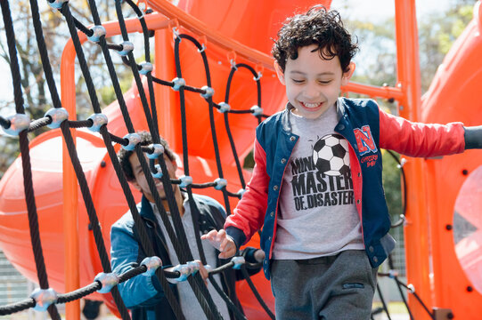 happy young boy running inside play park with his father behind him watching him