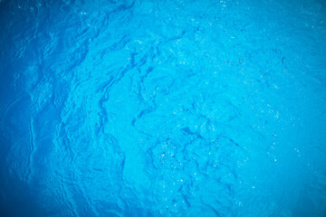 Water and air bubbles over blue background,sea wave ,Bokeh light background in the pool,Hotel swimming pool with sunny reflections.