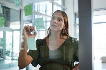Business woman, writing and glass board with thinking, ideas and sticky note with strategy for...