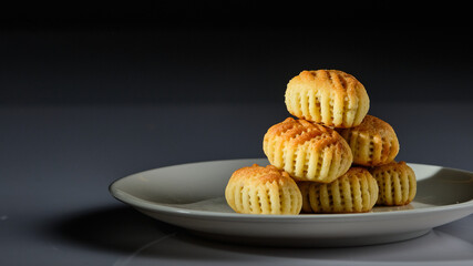 A plate of Arabic sweets with pistachios pictured on a white background and a gray and black background