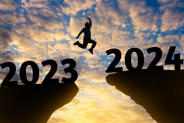Happy new year Silhouette sunset background.A man are jumping over to cliff and jump across 2023...