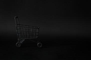 Black shoping cart on black background for Black Friday shopping sale concept.