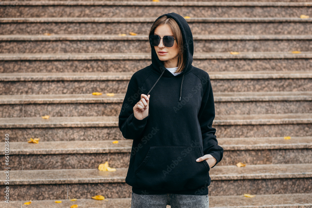 Wall mural Young woman in glasses and black hoodie