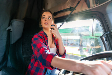 A beautiful woman drives a big truck and talks on the radio with the coordinator or road support