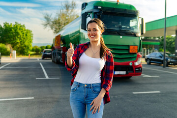 Junior female truck driver standing in front of her truck after she successfully completed her...